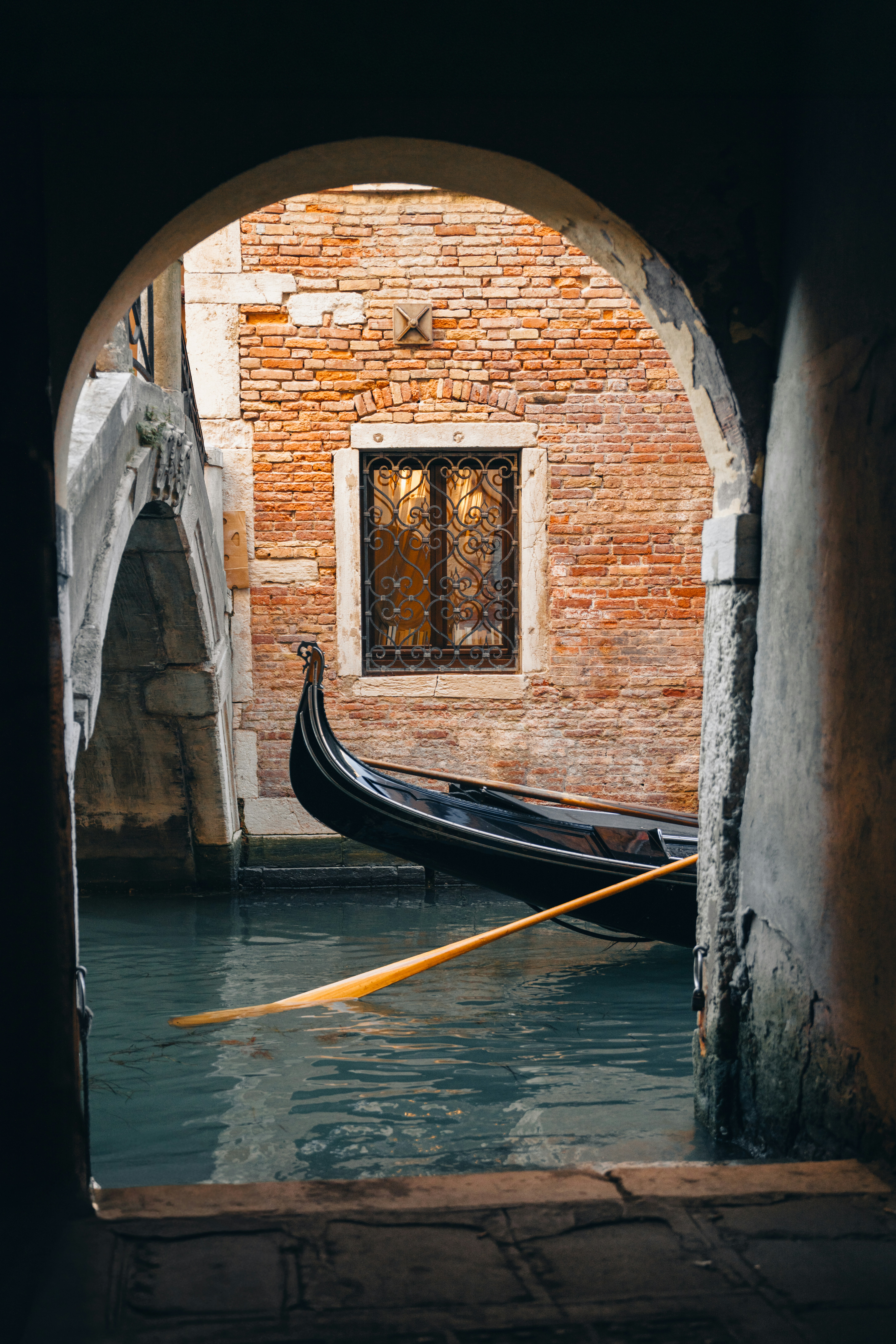 A gondola resting in a quiet Venetian canal at dusk